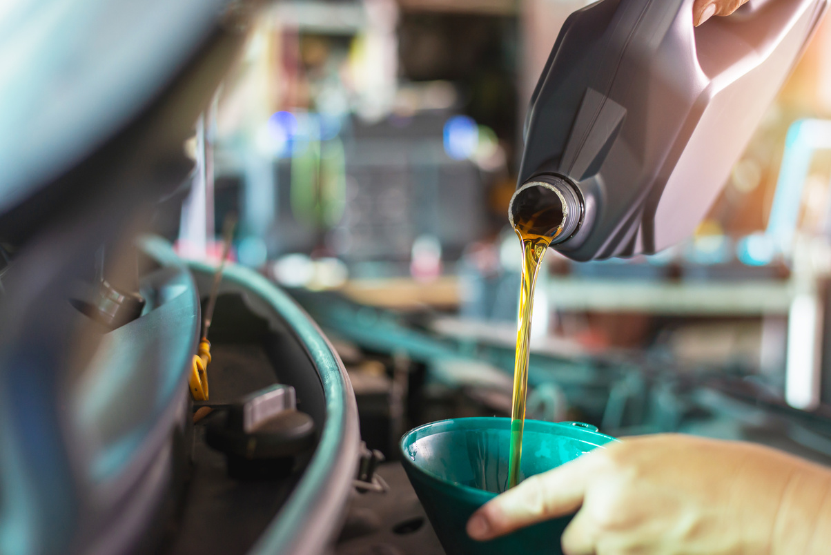 Pouring oil to car engine. Fresh oil poured during an oil change to a car.